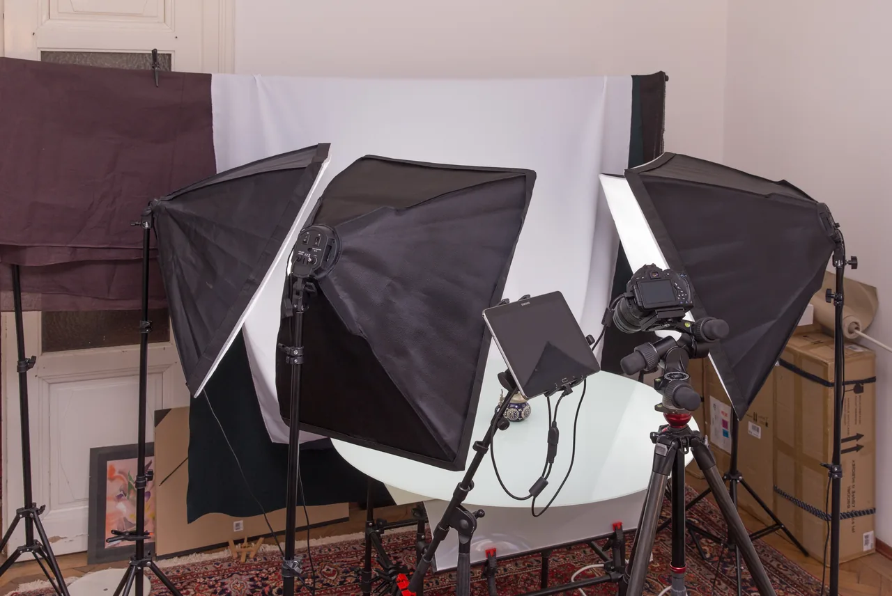 Studio de photographie de produits avec appareil sur tr&eacute;pied, &eacute;clairages diffusants et table de prise de vue.